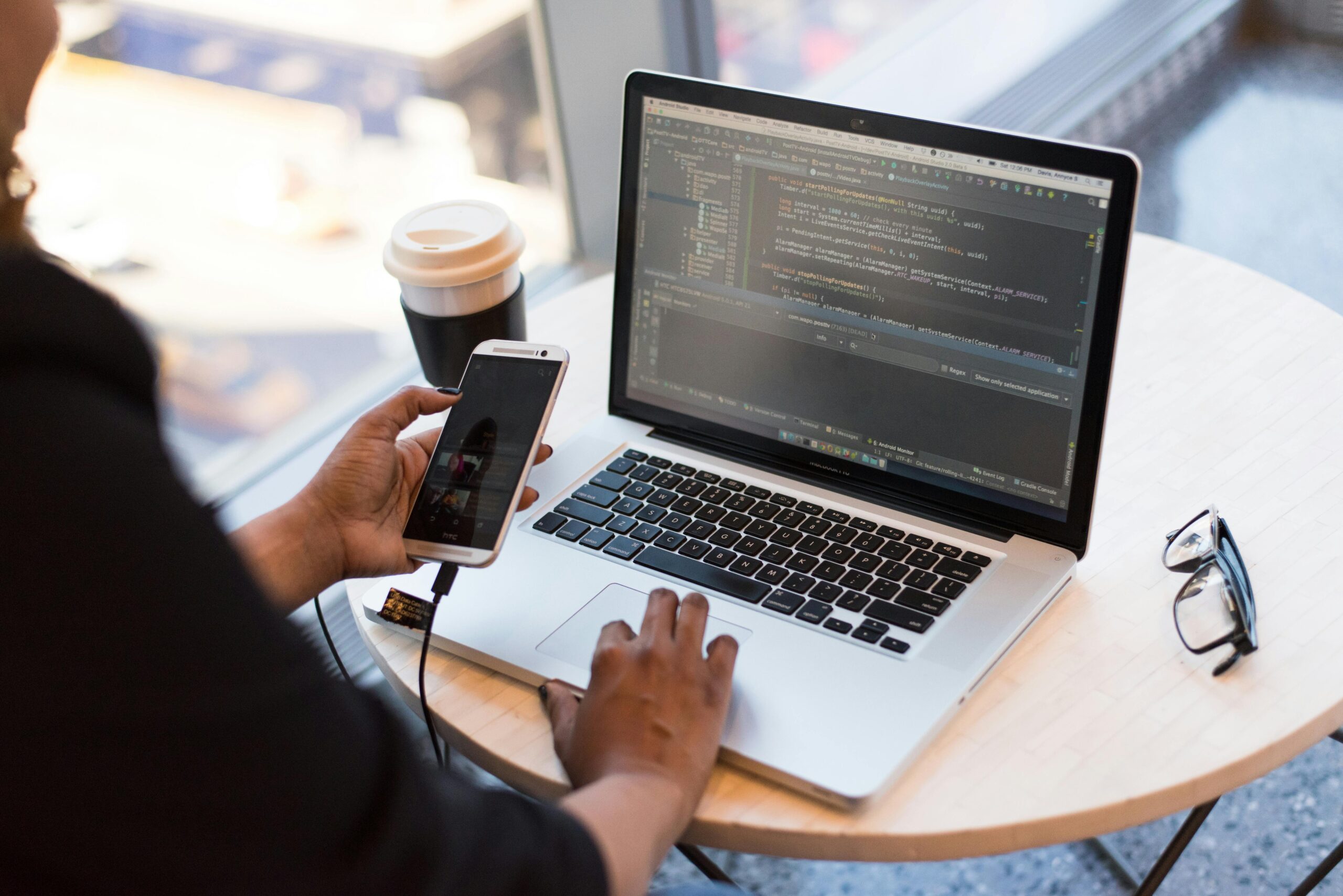 a person holding a mobile that is connected to a laptop