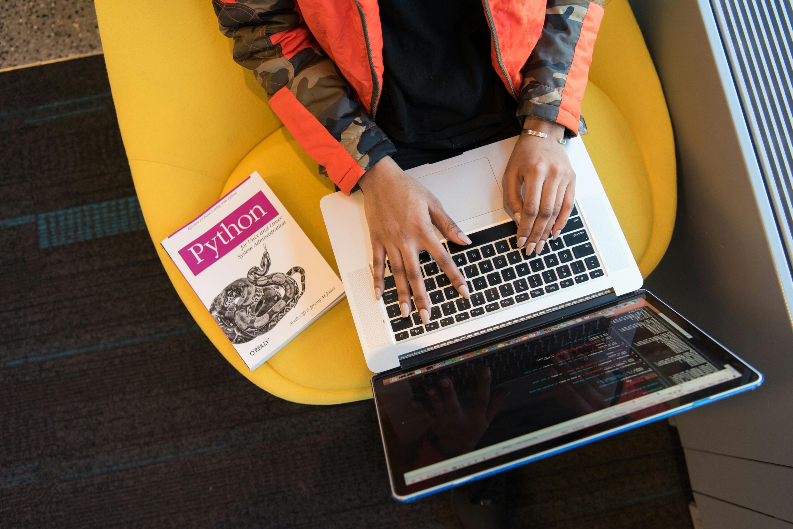 a person sitting in an orange chair with a laptop on their lap